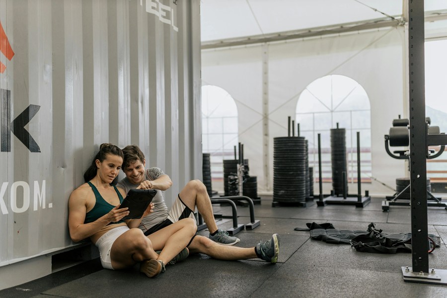 Personlig tränare och kund tittar på träningsprogram på en surfplatta